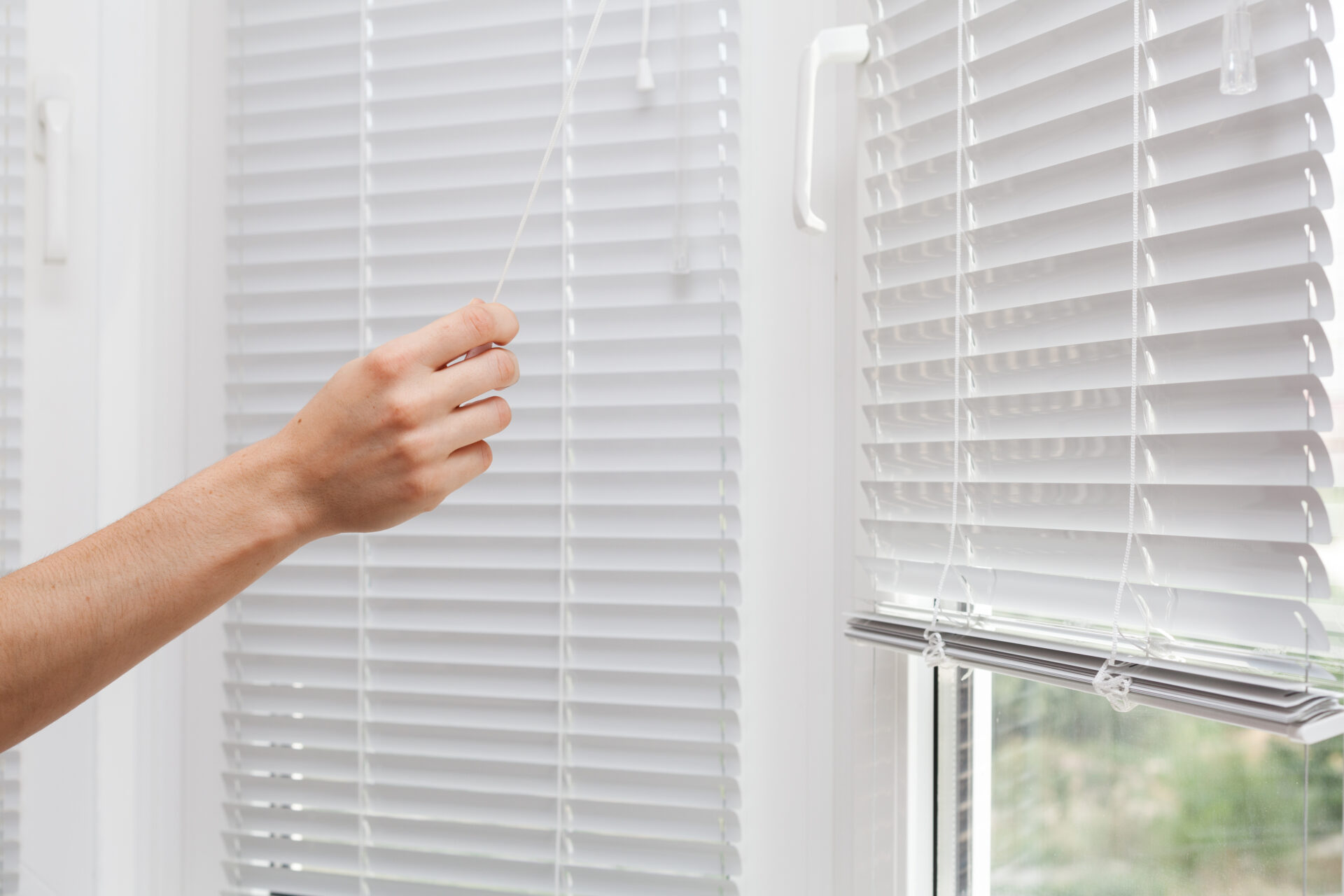 Adjusting white window blinds with a cord