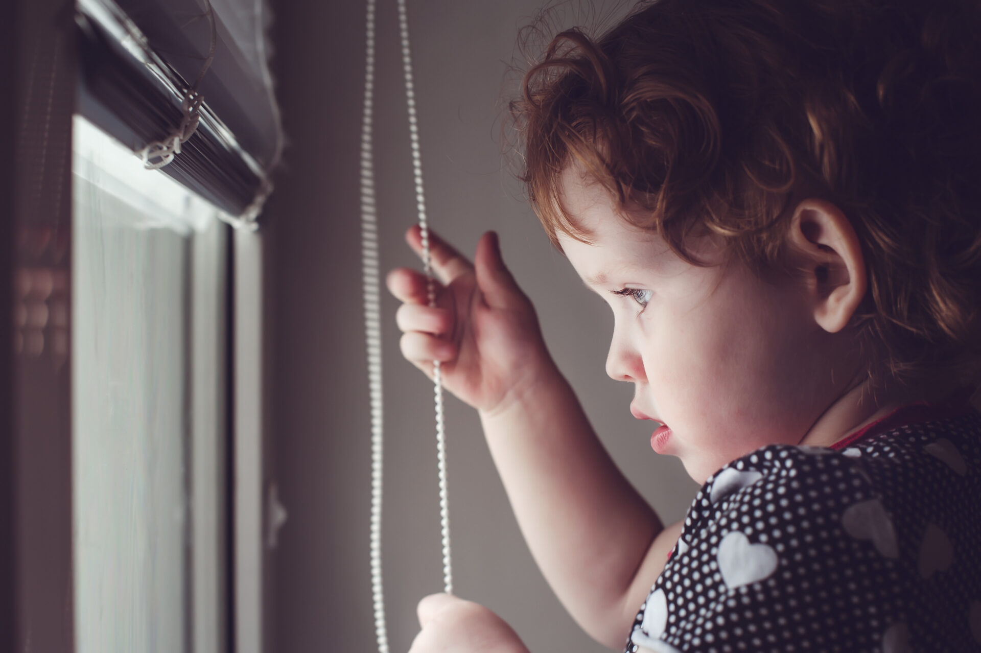 Child pulling the cord on a window blind